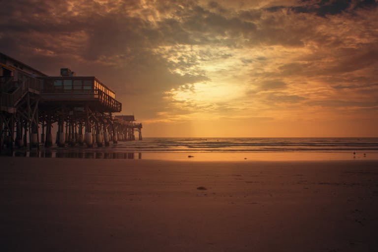 Stunning sunset view of Cocoa Beach Pier, Florida, with a vibrant sky and calm ocean.