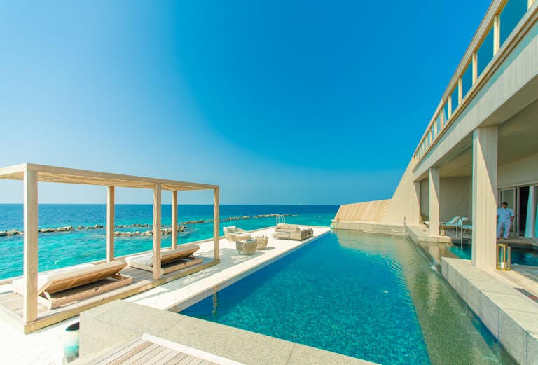 Stunning view of a luxury resort in Maldives with an infinity pool overlooking the ocean.