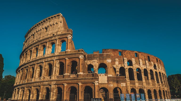 Stunning view of the ancient Roman Colosseum in Rome, Italy, captured at sunset showcasing its historic arches.