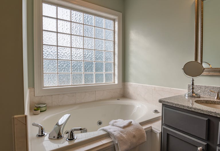 Stylish modern bathroom featuring a luxury bathtub, sleek sink, and large window. Perfect for relaxation.