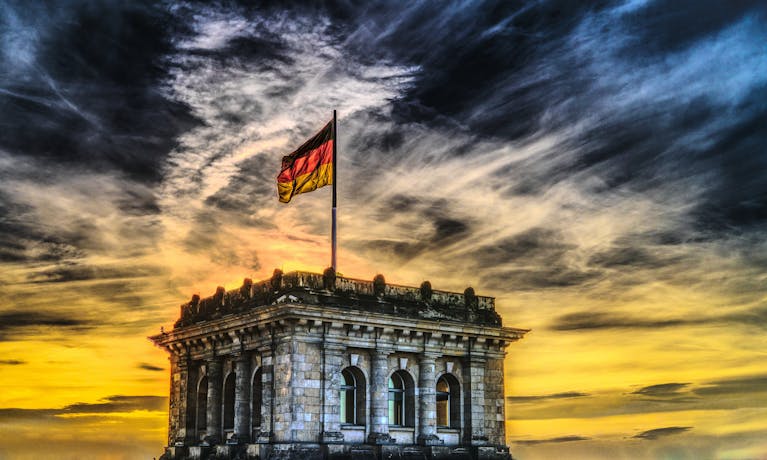 Vibrant sunset over a historic Berlin monument with the German flag waving.