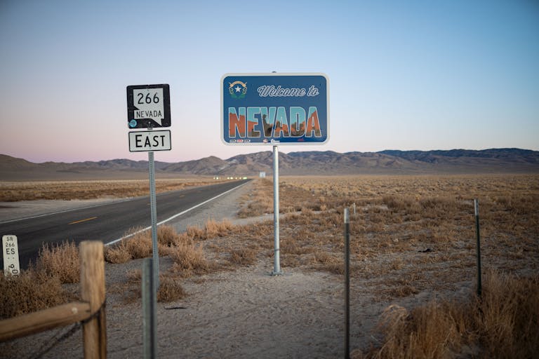 A scenic view of the Nevada desert highway at dawn with a welcome sign and empty road.