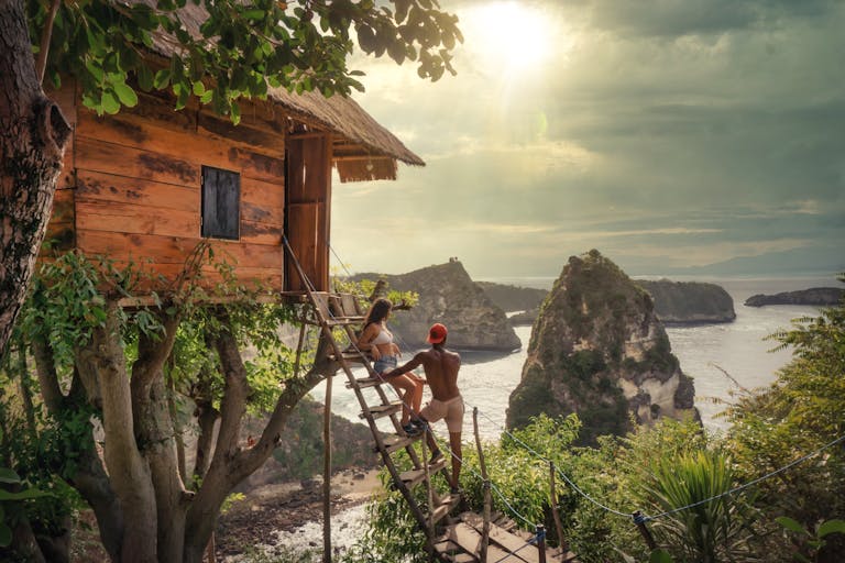 Couple relaxing on a tree house with stunning ocean views in Bali, Indonesia.