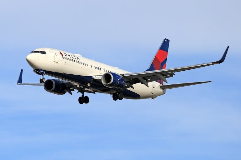 Delta Airlines aircraft soaring in clear blue sky, showcasing aviation travel.