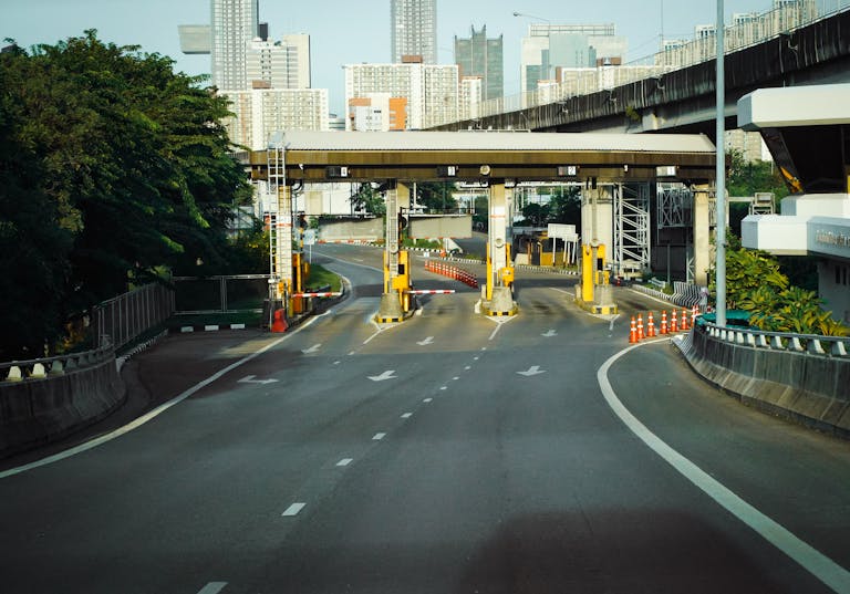 Toll booth on a Bangkok highway with urban skyscrapers in the background, during a clear day.