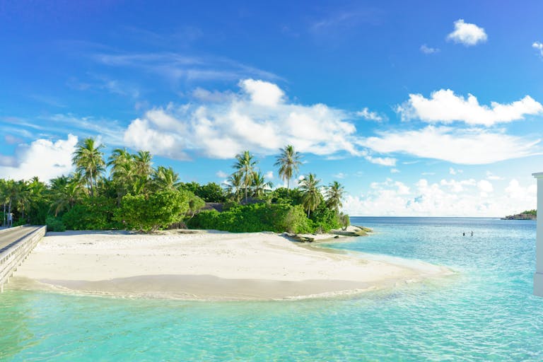 Experience the serene beauty of a tropical Maldives beach with azure waters and lush greenery.